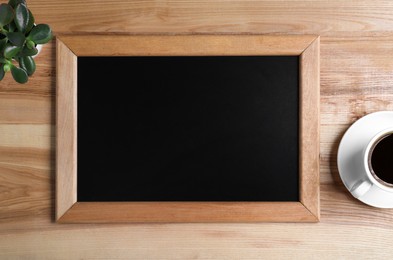 Photo of Clean small chalkboard, coffee and plant on wooden table, flat lay