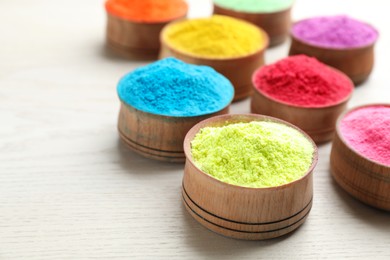 Colorful powder dyes on white wooden background, closeup. Holi festival