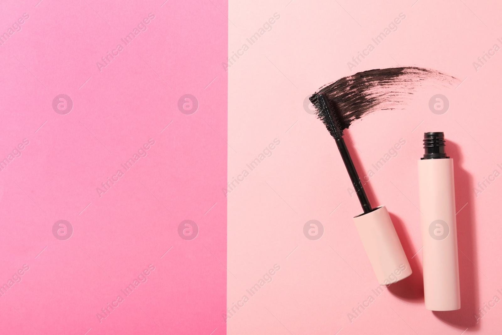 Photo of Mascara and smear on pink background, flat lay with space for text. Makeup product