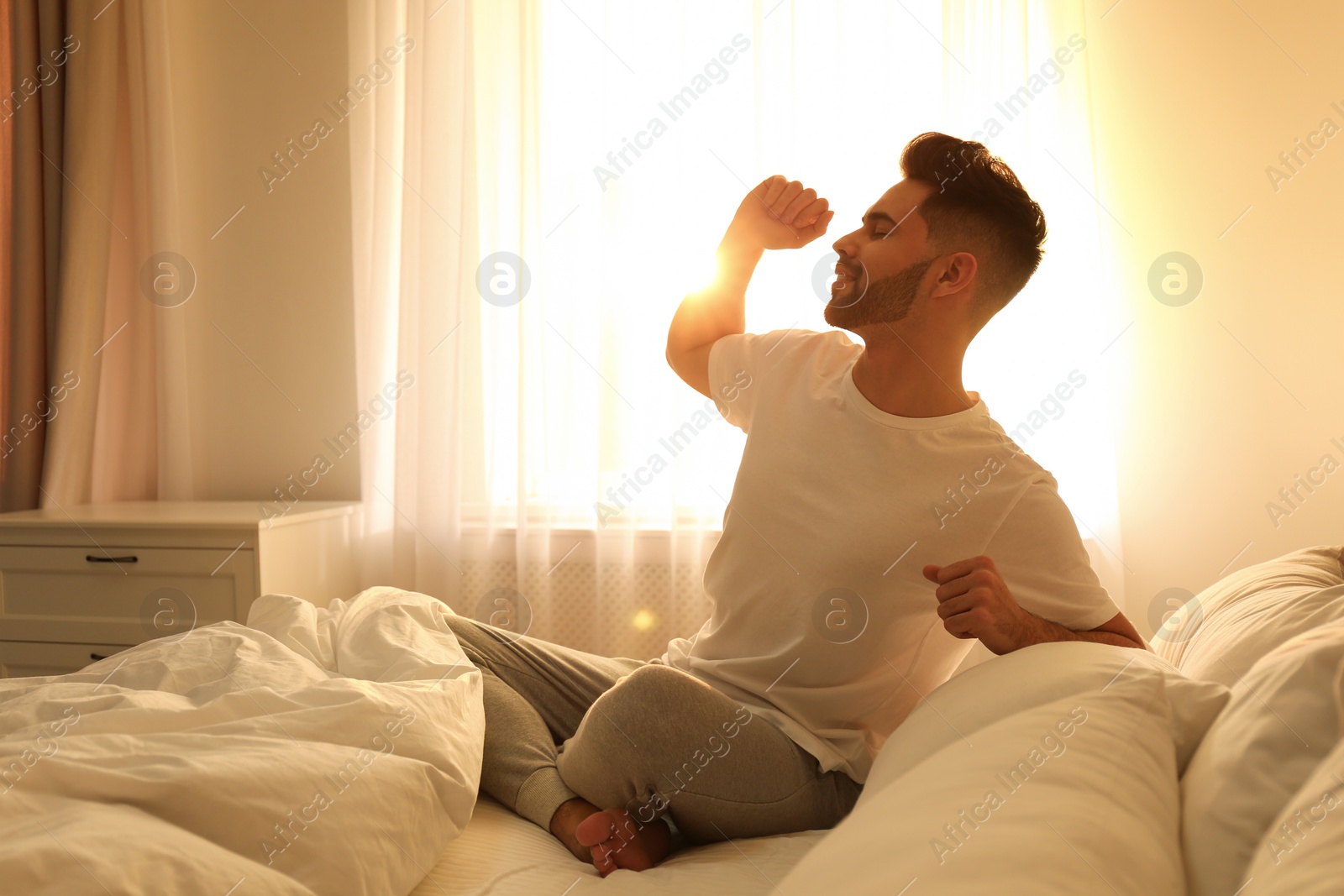 Photo of Young man stretching on bed at home. Lazy morning