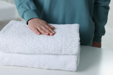 Woman touching soft white towel indoors, closeup