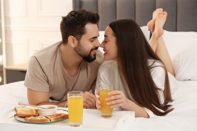 Happy couple having breakfast on bed at home