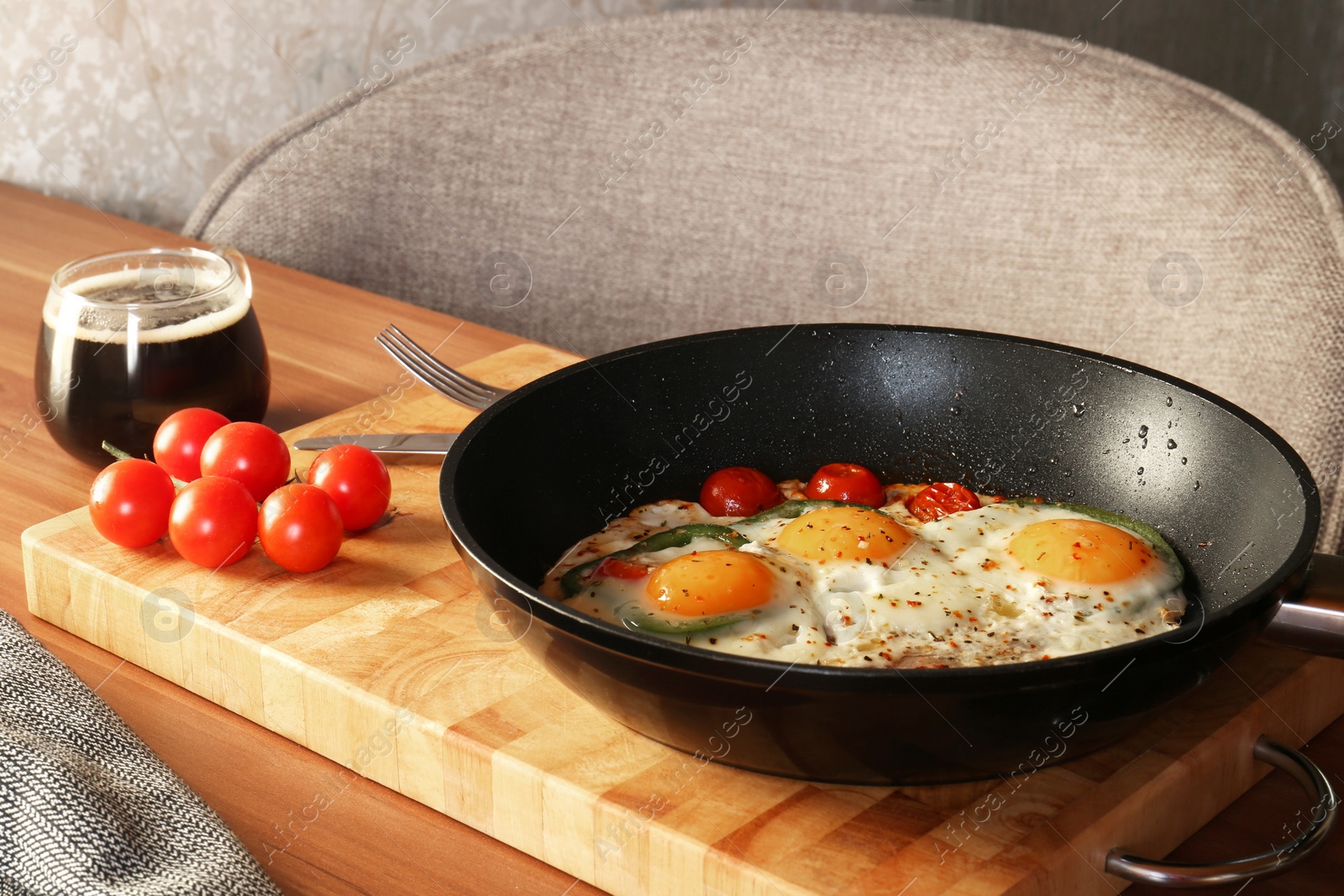 Photo of Delicious fried eggs with tomatoes and pepper served on wooden table
