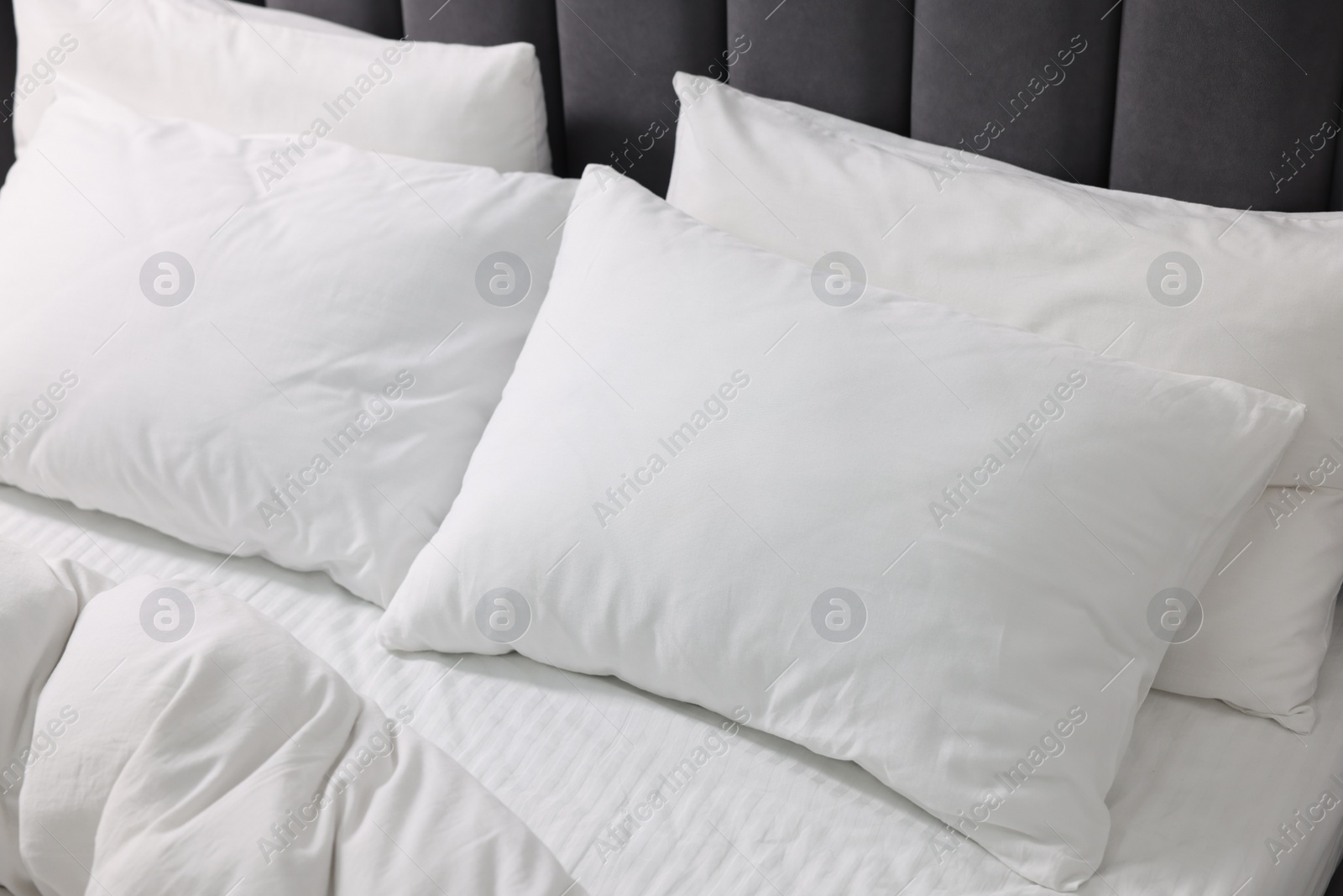 Photo of Soft white pillows and duvet on bed