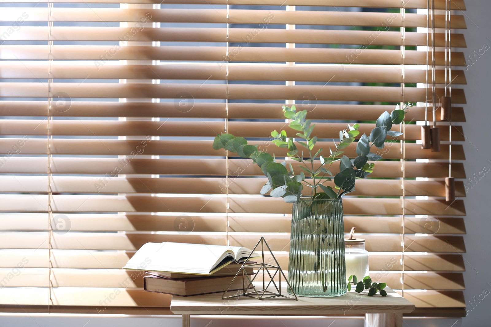 Photo of Vase with fresh eucalyptus branches on table near window in room. Interior design