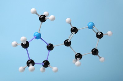 Photo of Molecule of nicotine on light blue background. Chemical model
