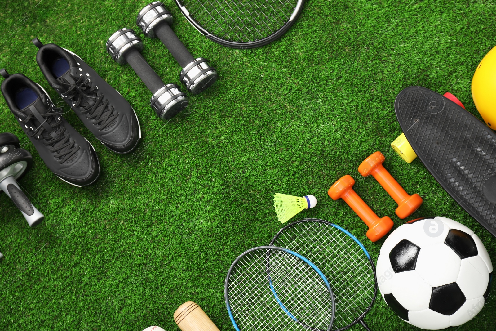 Photo of Different sports equipment on green grass, flat lay. Space for text