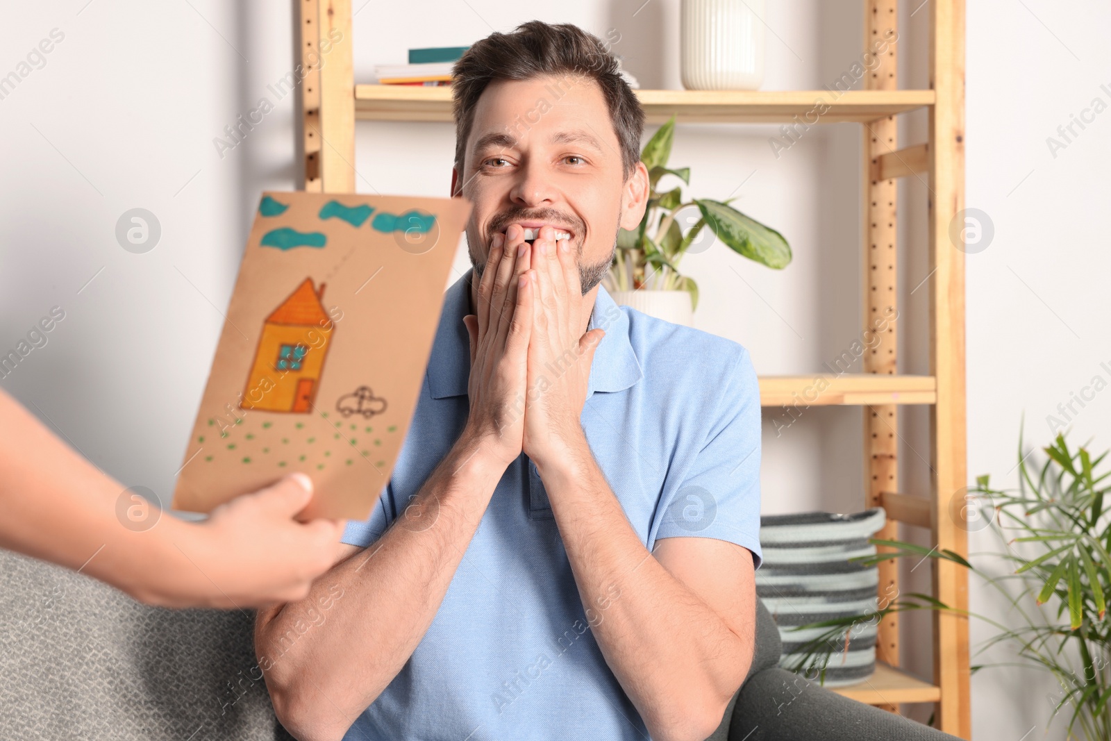 Photo of Happy man receiving greeting card from his son at home