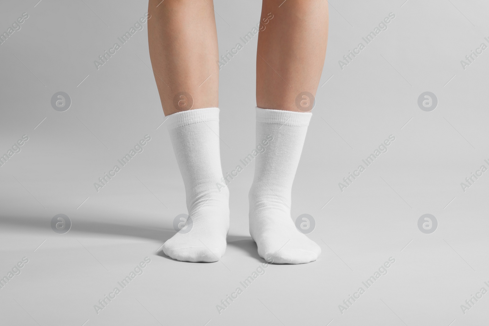 Photo of Woman in stylish white socks on light grey background, closeup