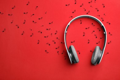 Image of Headphones and musical notes on red background, top view