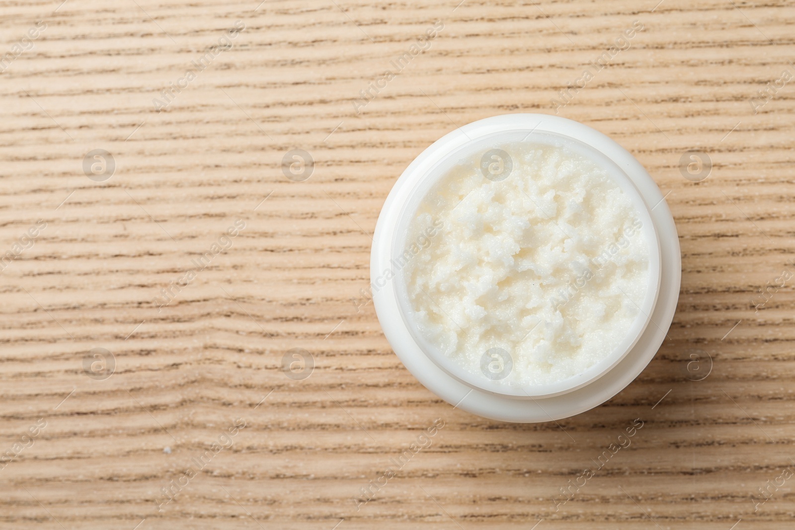 Photo of Jar of shea butter and space for text on wooden background, top view