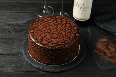 Photo of Delicious truffle cake and chocolate pieces on black wooden table