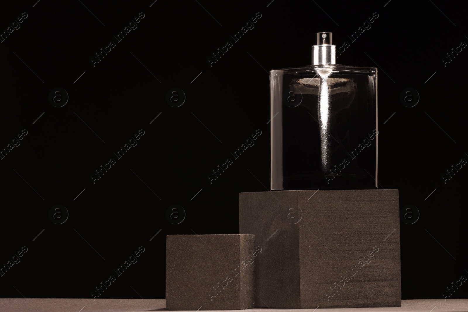 Photo of Luxury men`s perfume in bottle against black background, space for text