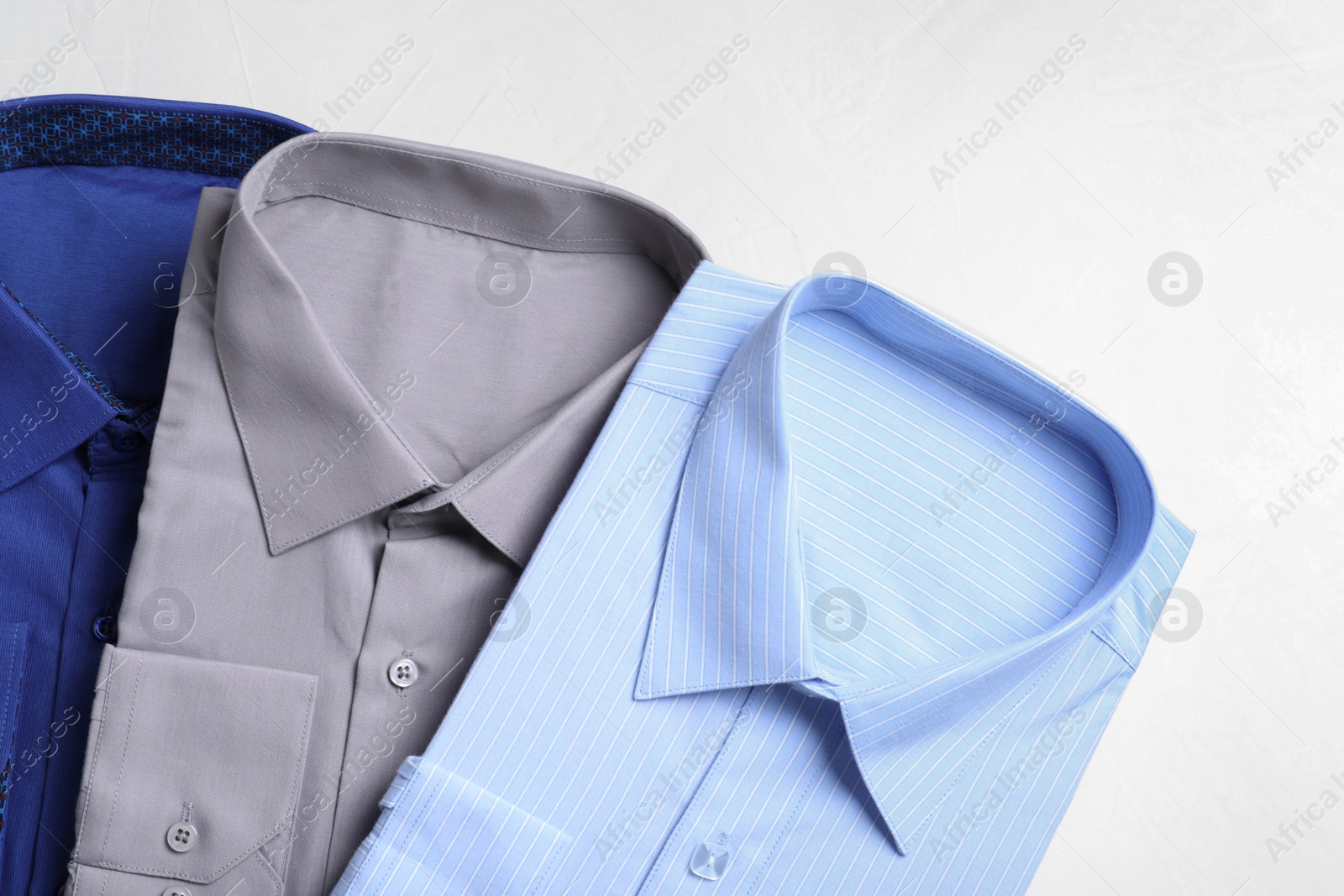 Photo of Stylish shirts on light table, flat lay. Dry-cleaning service