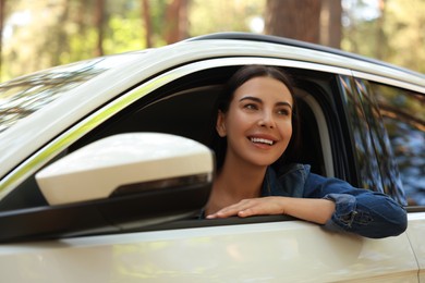 Photo of Happy young woman looking out of car window, view from outside. Enjoying trip