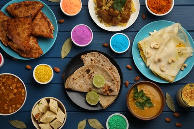 Photo of Traditional Indian food and color powders on blue wooden table, flat lay. Holi festival celebration