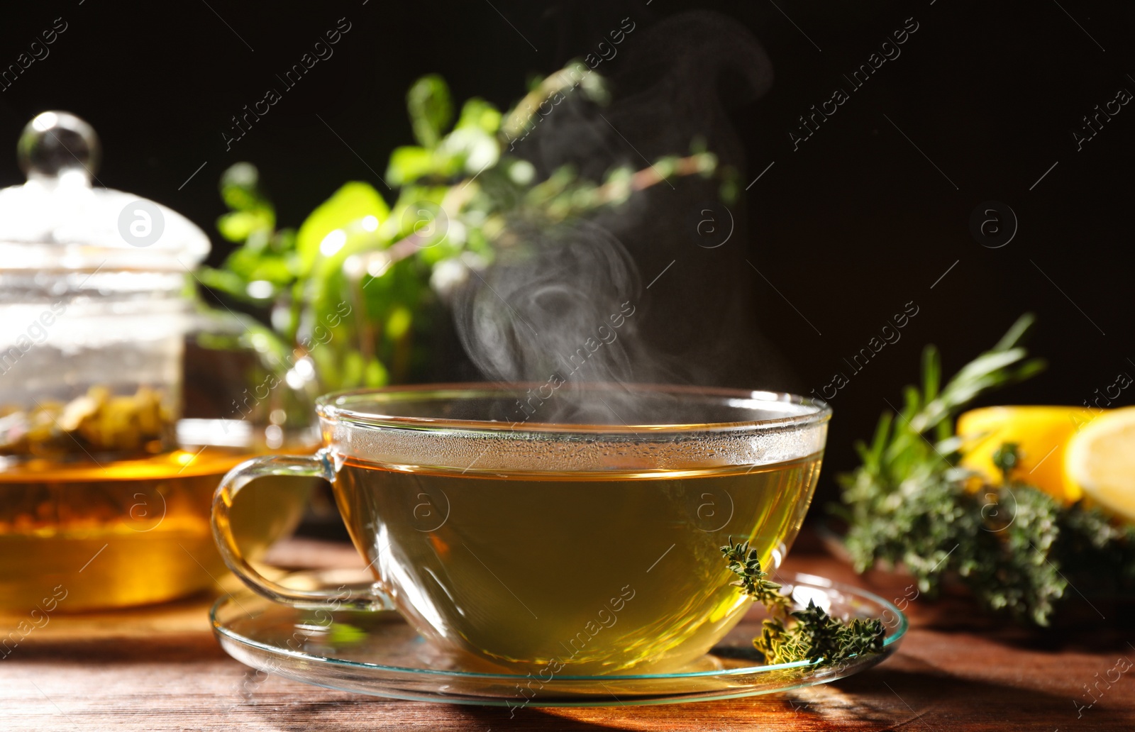 Photo of Cup of aromatic herbal tea and thyme on wooden table