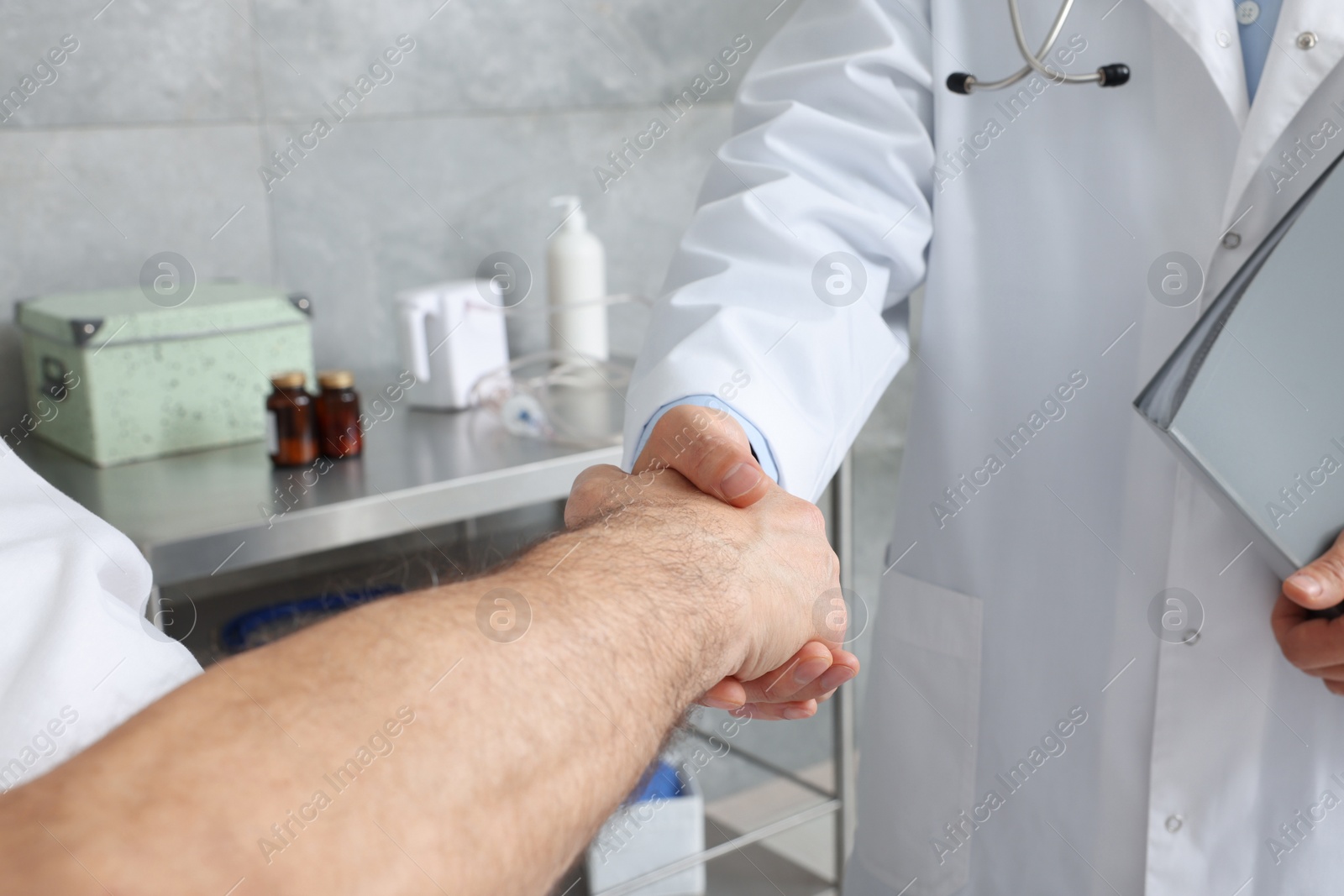 Photo of Doctor shaking hands with senior patient in hospital, closeup