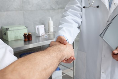 Doctor shaking hands with senior patient in hospital, closeup