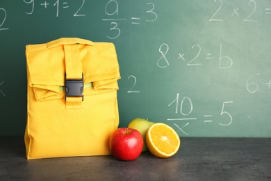 Photo of Healthy food for school child on table near chalkboard with written sums
