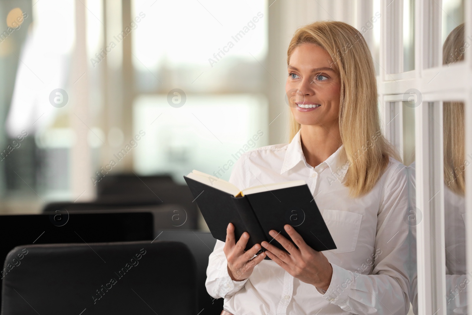 Photo of Smiling woman with book in office, space for text. Lawyer, businesswoman, accountant or manager