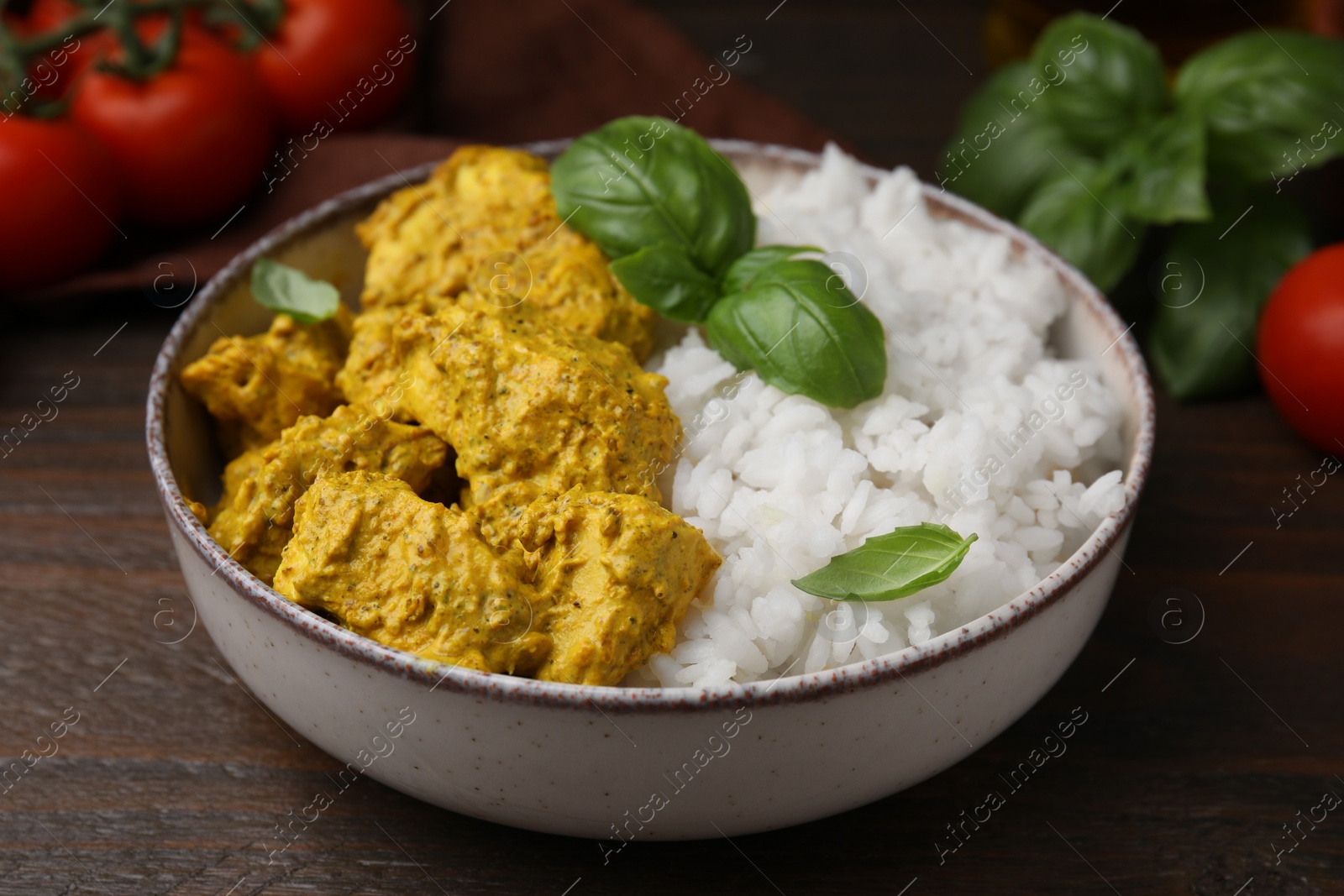 Photo of Delicious rice and chicken with curry sauce on wooden table, closeup