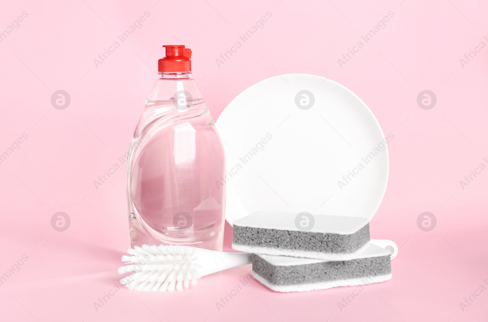 Photo of Detergent, plate and sponges on pink background. Clean dishes