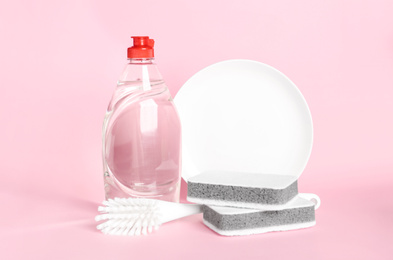 Photo of Detergent, plate and sponges on pink background. Clean dishes