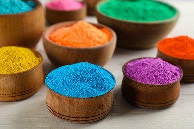 Colorful powder dyes on white wooden background, closeup. Holi festival