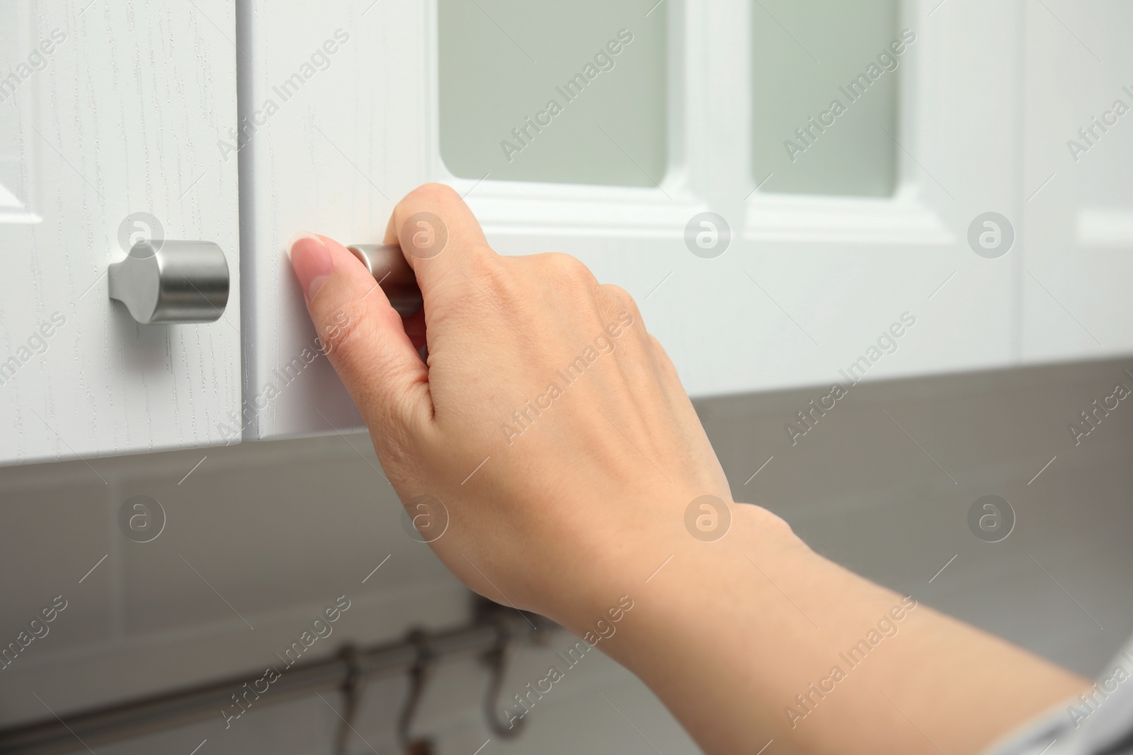 Photo of Woman opening cabinet door at home, closeup