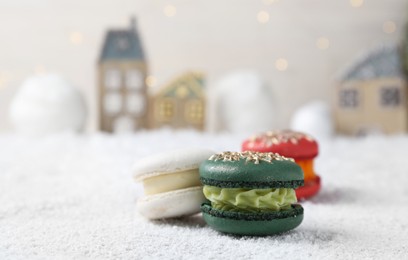 Photo of Different decorated Christmas macarons on table with artificial snow