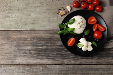 Delicious mozzarella with tomatoes and basil leaves on wooden table. flat lay. Space for text