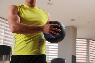 Muscular man exercising with medicine ball in gym, closeup