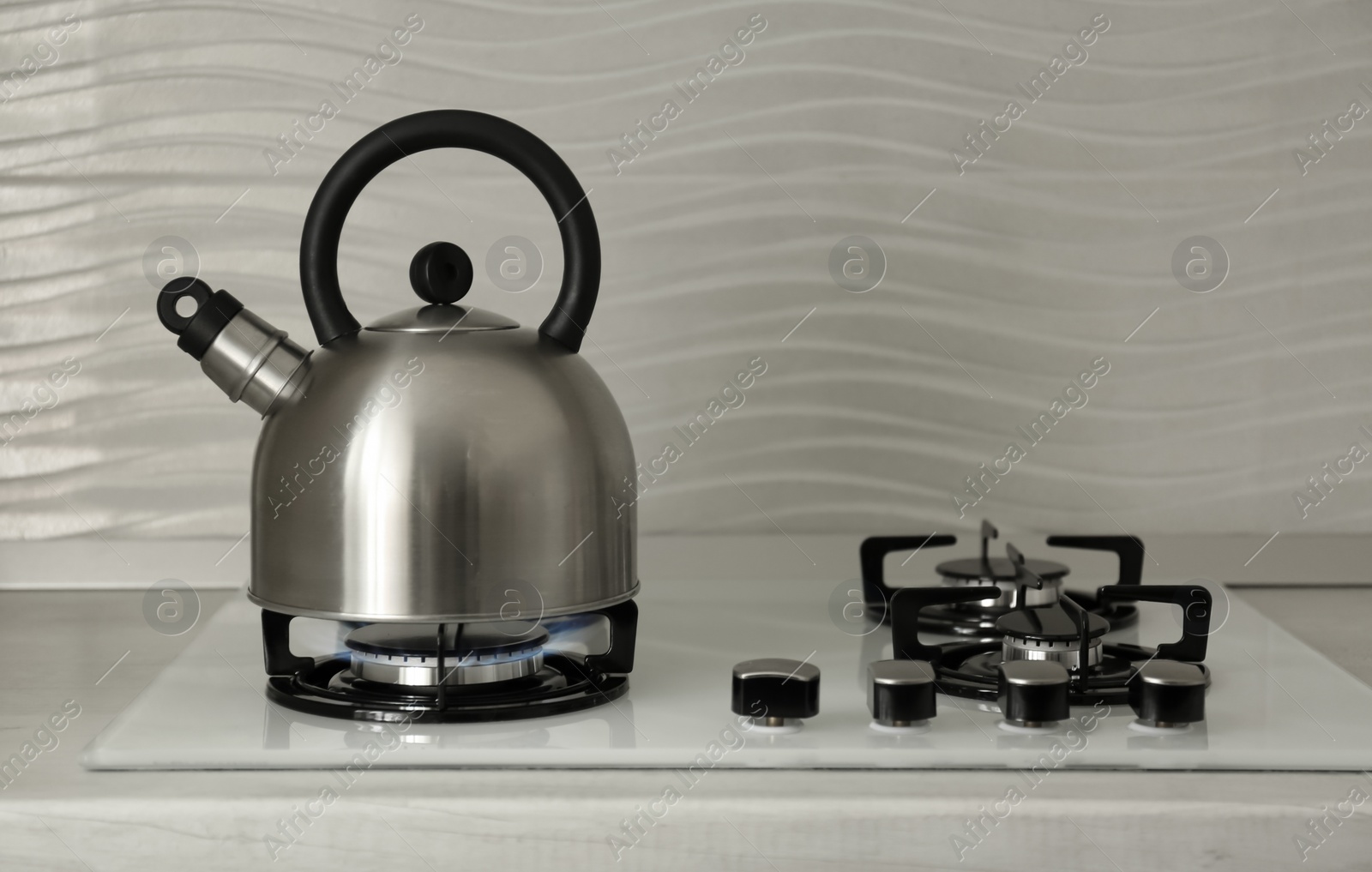 Photo of Steel kettle with whistle on modern gas stove. Space for text