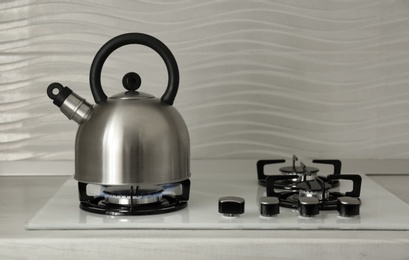 Photo of Steel kettle with whistle on modern gas stove. Space for text