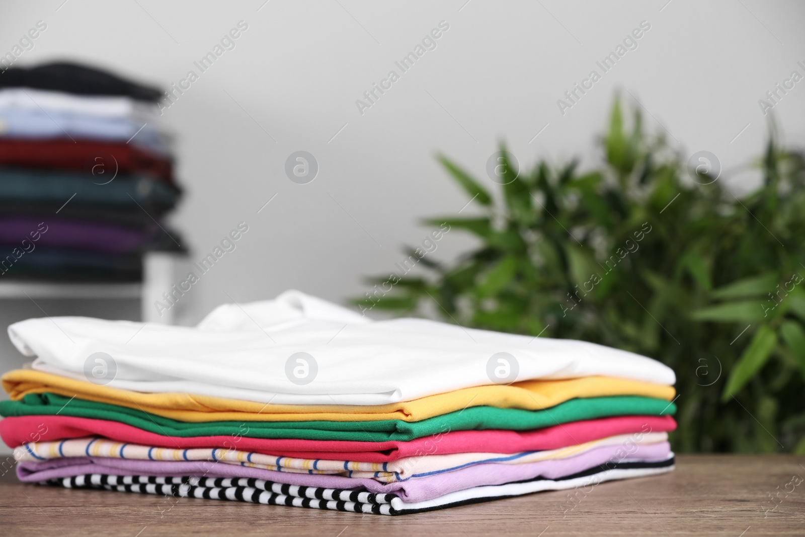 Photo of Pile of ironed clothes on table in room. Space for text