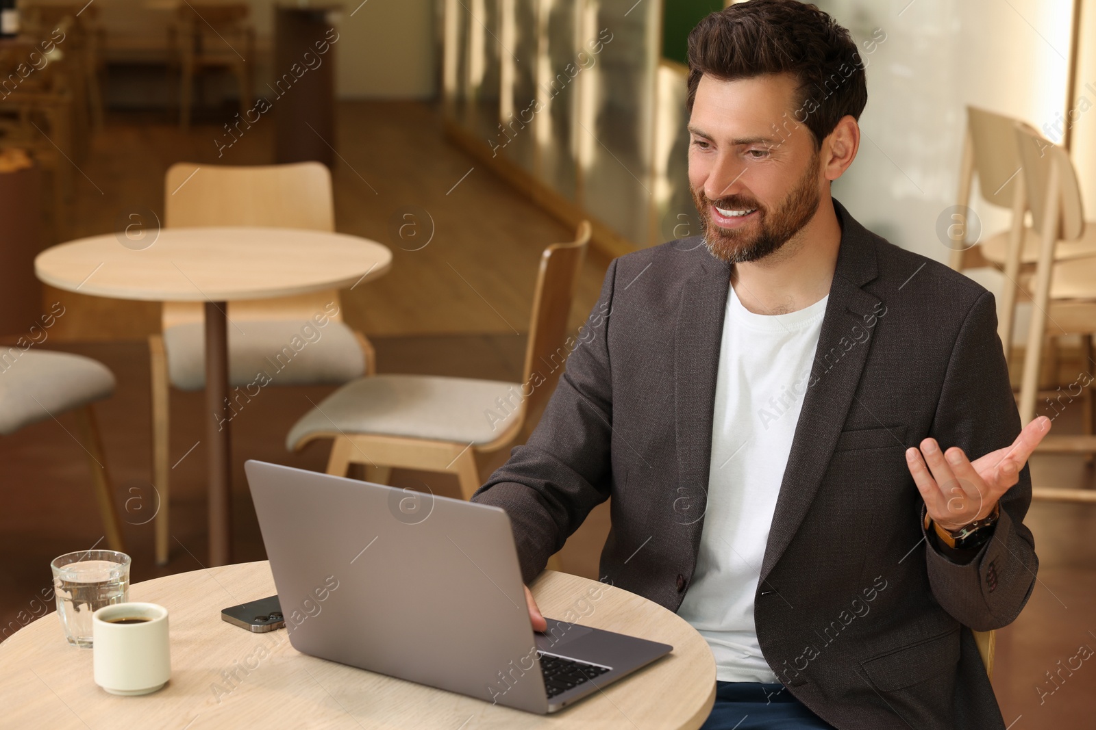 Photo of Man having video chat via laptop in cafe