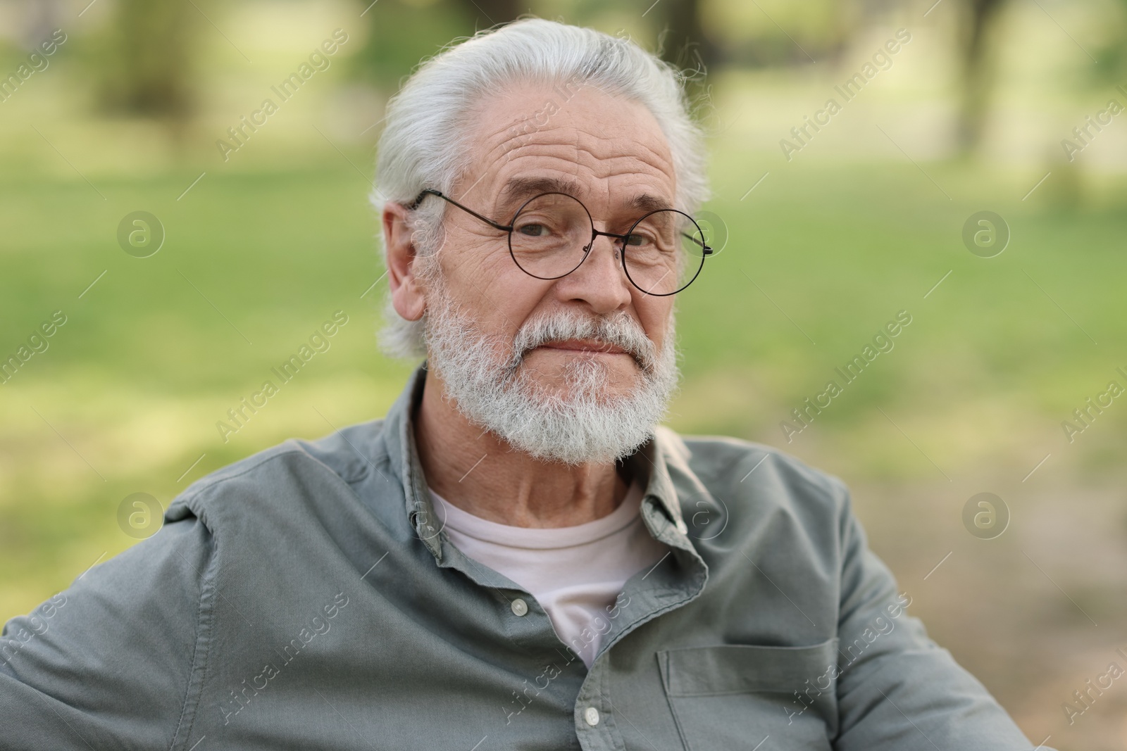 Photo of Portrait of happy grandpa with glasses in park