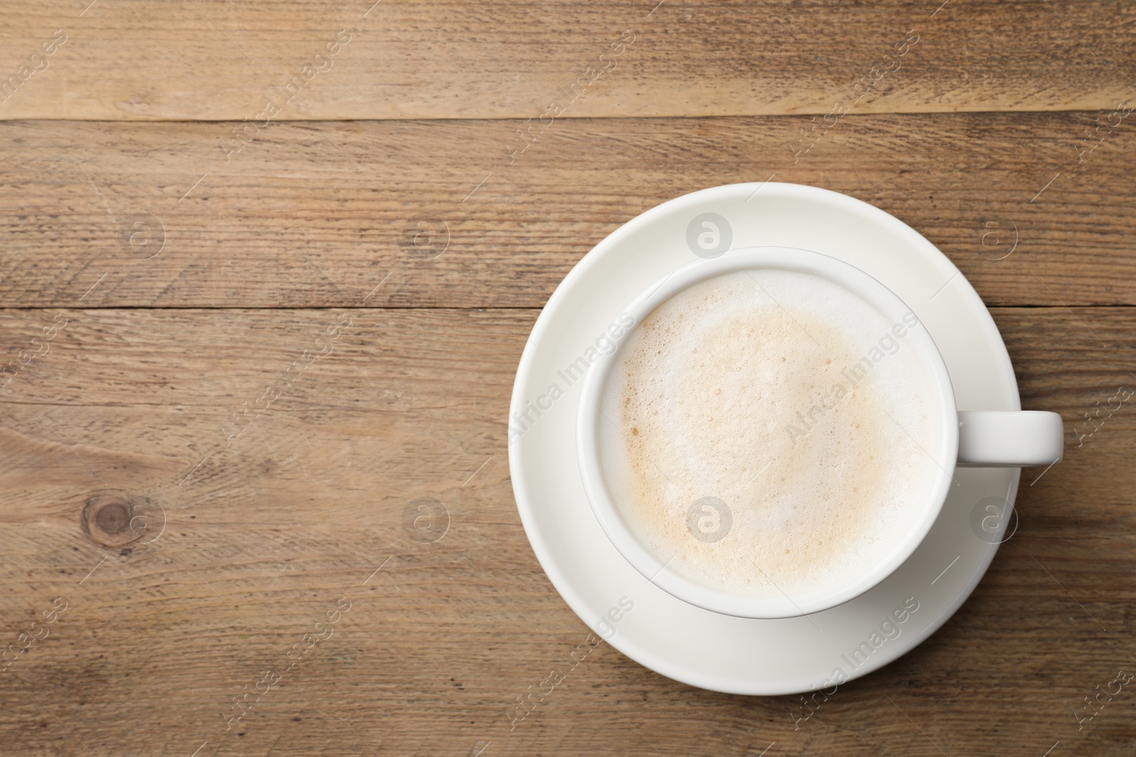 Photo of Cup of aromatic coffee on wooden table, top view. Space for text