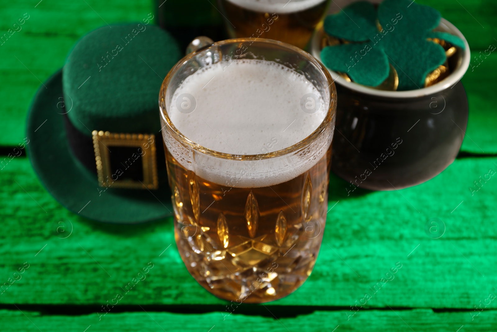 Image of St. Patrick's day. Beer, leprechaun hat, pot of gold and decorative clover leaf on green wooden table