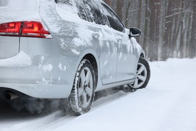 Photo of Car with winter tires on snowy road outdoors, space for text