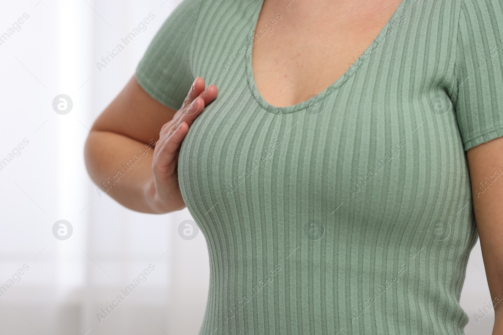 Photo of Mammology. Woman doing breast self-examination indoors, closeup