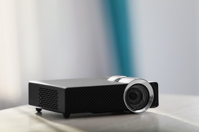 Photo of Modern video projector on white table indoors