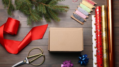 Box, wrapping paper and scissors on wooden table, flat lay