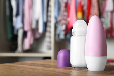 Photo of Natural female roll-on deodorants on wooden table indoors. Space for text