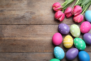 Photo of Colorful eggs and tulips on wooden background, flat lay with space for text. Happy Easter