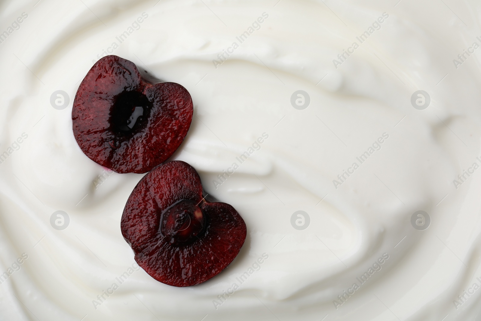 Photo of Tasty yogurt with cut cherry as background, top view. Space for text