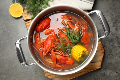 Photo of Fresh delicious crayfishes in pot on grey table, flat lay