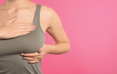 Woman checking her breast on color background, closeup. Space for text