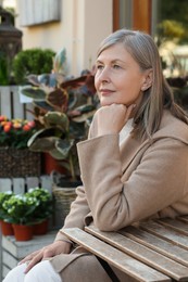 Beautiful senior woman sitting in outdoor cafe, space for text